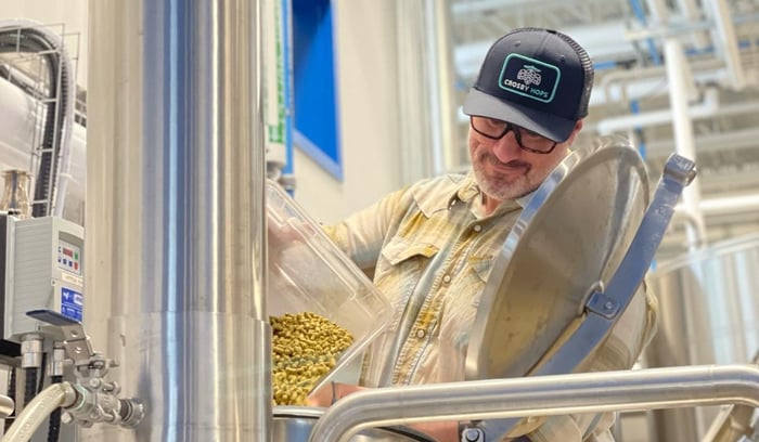 Crosby Hops Team Member Adds Hop Pellets to Fermenting Beer